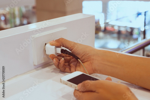 Woman hand hold the charging cable plugging the smart phone