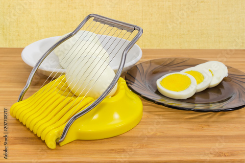 Egg slicer and boiled eggs on the saucers closeup