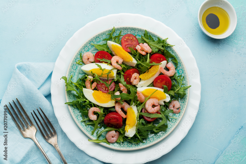 Arugula, cucumber, tomato, eggs and shrimp salad with soy sauce on ceramic plate. Selective focus. Top view. Arugula, cucumber, tomato, eggs and shrimp salad with soy sauce on ceramic plate. Selective focus. Top view.