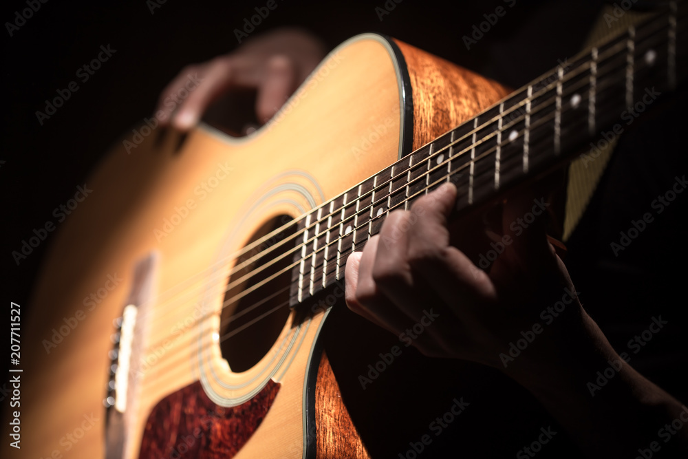 Obraz premium Man playing acoustic guitar on dark background. A musical concept.
