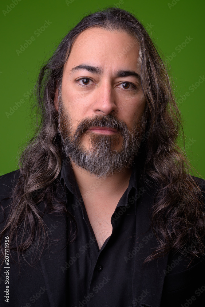Studio shot of mature handsome bearded multi-ethnic businessman with long hair