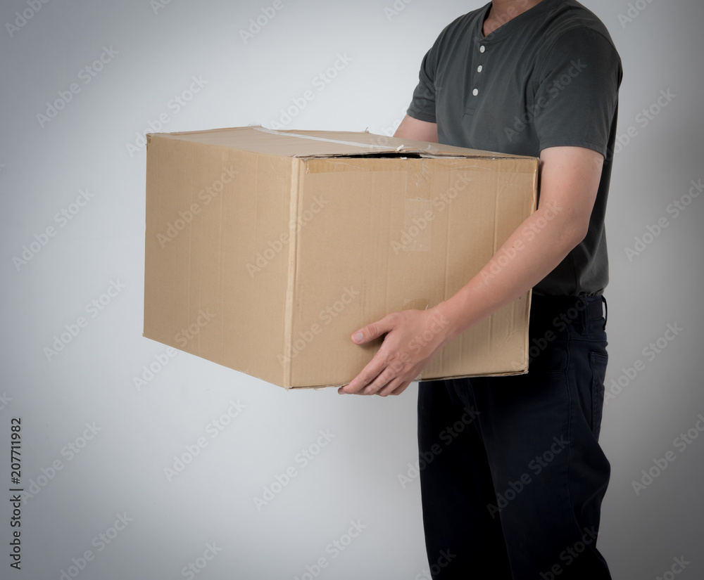 Delivery man holding cardboard box on gray background Delivery man holding cardboard box on gray background