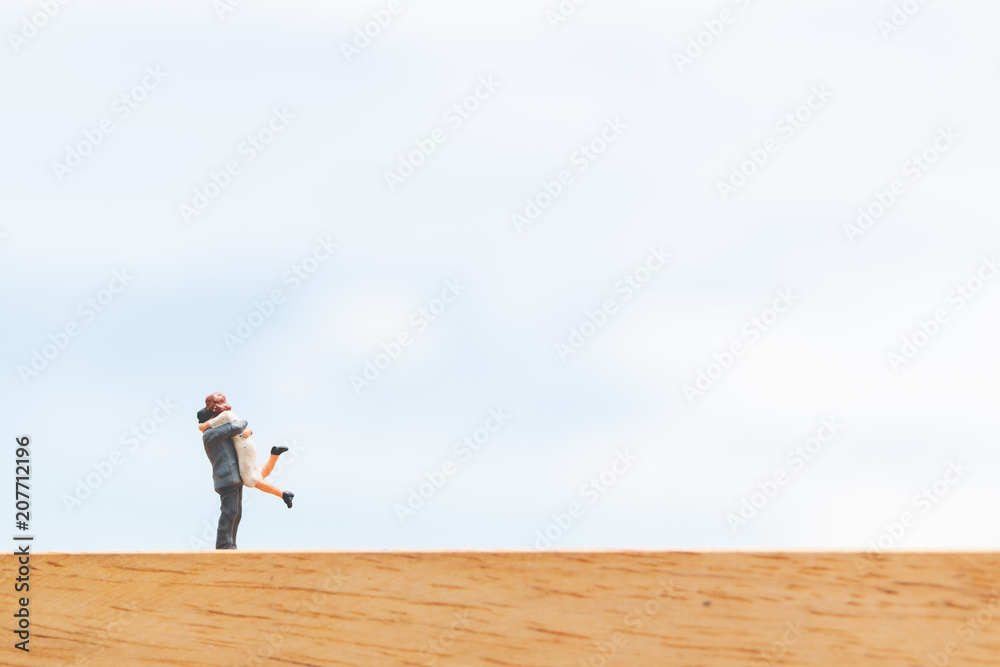 Couple hugging on wooden floor with blue sky background