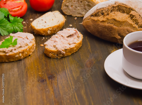 bread and sandwiches with pate and a Cup of tea and tomatoes on a wooden background 