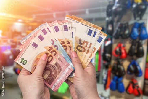 Shopping in sport outfit magazine, hands with euro banknotes