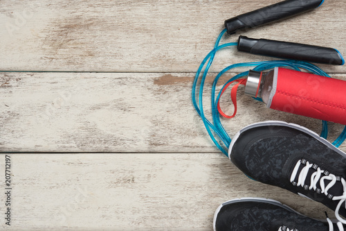 Skipping rope,Running shoes and drink bottle on wood background,top view