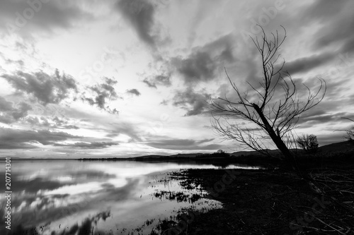 Lake shore at sunset, with perfect reflections of some clouds on