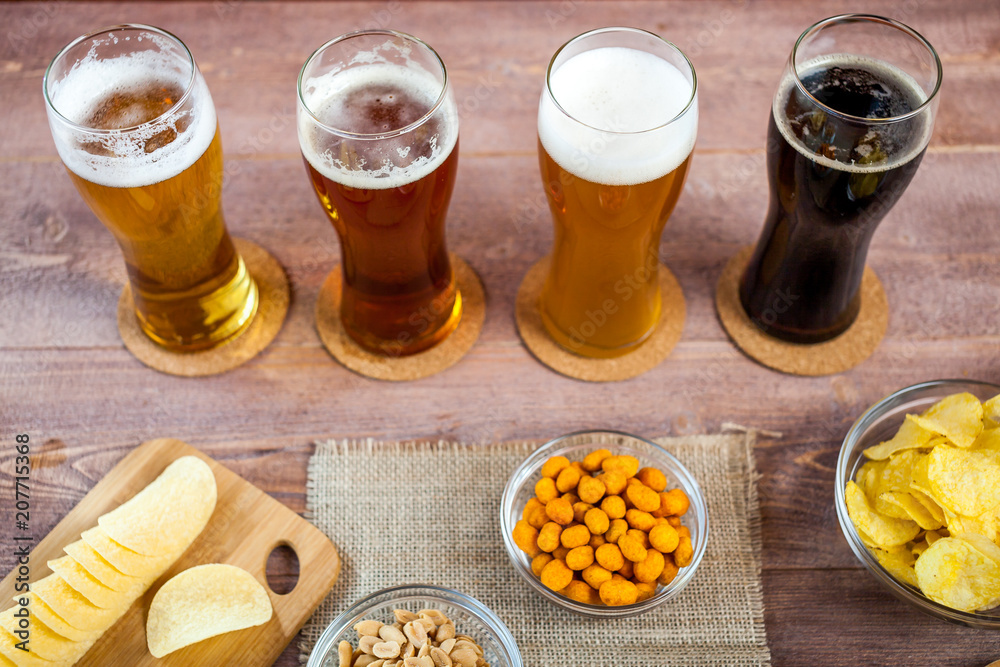 glasses of light and dark beer with assorted snacks on a wooden table background. bachelor party, pub, bar or degustation concept glasses of light and dark beer with assorted snacks on a wooden table background. bachelor party, pub, bar or degustation concept