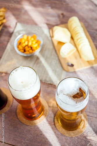 glasses of light and dark beer with assorted snacks on a wooden table background. bachelor party, pub, bar or degustation concept