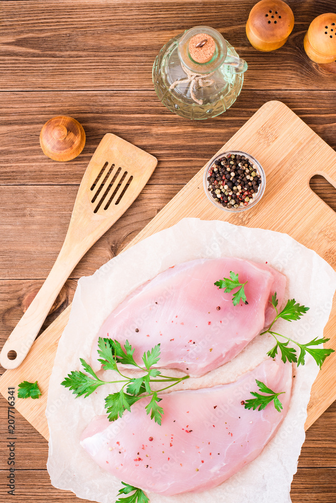 Raw turkey fillet in spices and herbs on a cutting board on a wooden table. Top view Raw turkey fillet in spices and herbs on a cutting board on a wooden table. Top view