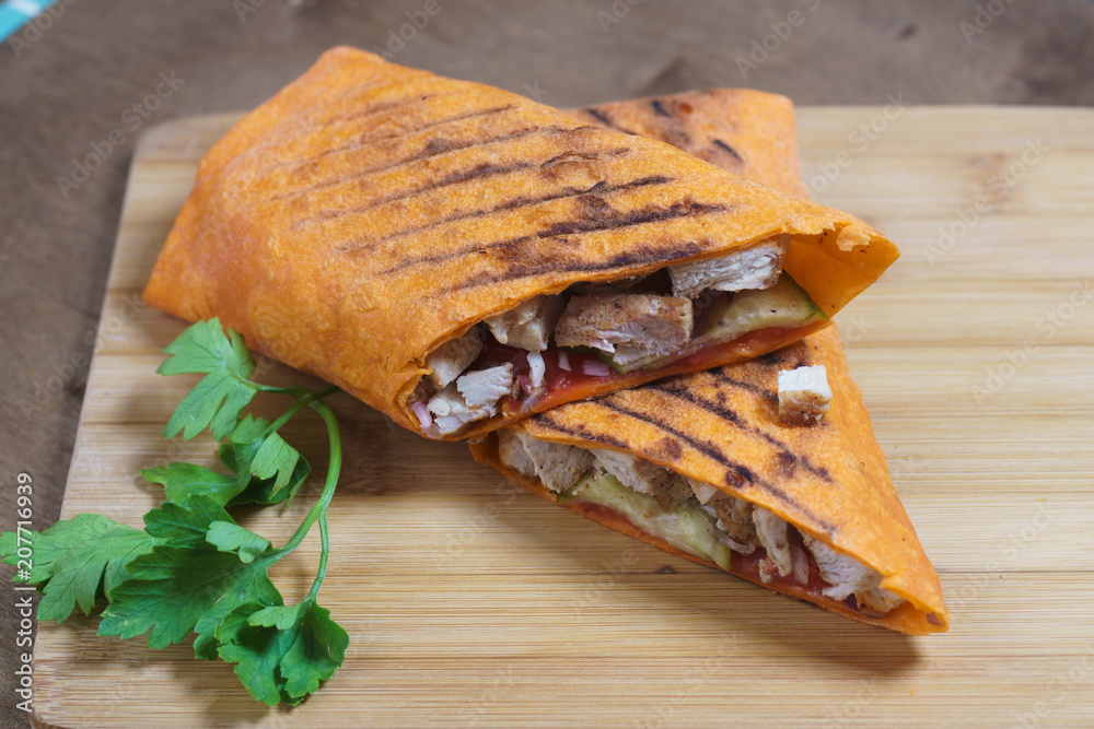 Shawarma chicken roll in a pita on wooden background. Shawarma chicken roll in a pita on wooden background.