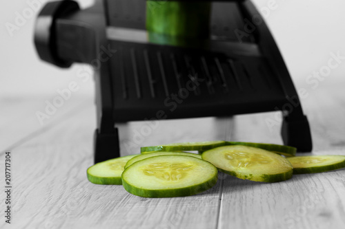 sliced cucumber with mandoline on a grey wood kitchen worktop with selective colour photo