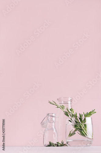 Modern simple art pink home decor with green plant in transparent vases on soft light white wood table, vertical.