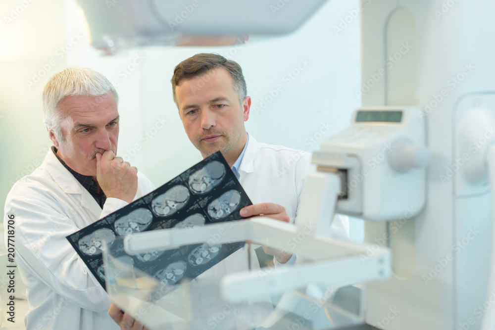 two yound doctors examining a x-ray film at the diaphanoscope two yound doctors examining a x-ray film at the diaphanoscope