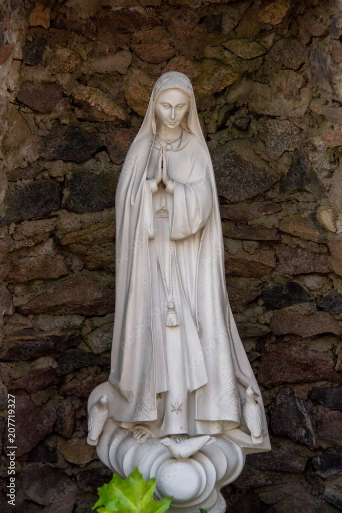 White figure of Mary standing in a stone environment