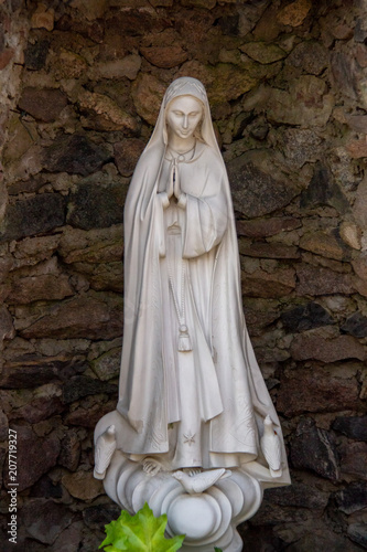 White figure of Mary standing in a stone environment
