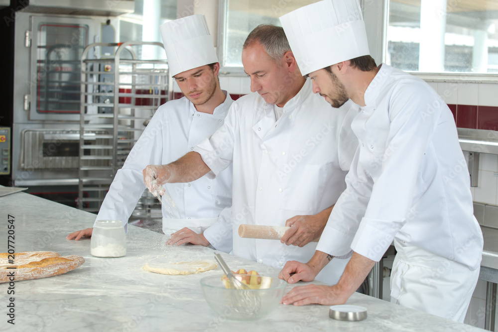 three bakers wearing work coats and baking