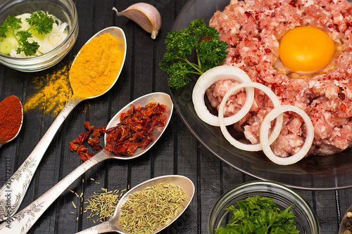 Minced meat. Ground meat with ingredients for cooking on a black background.