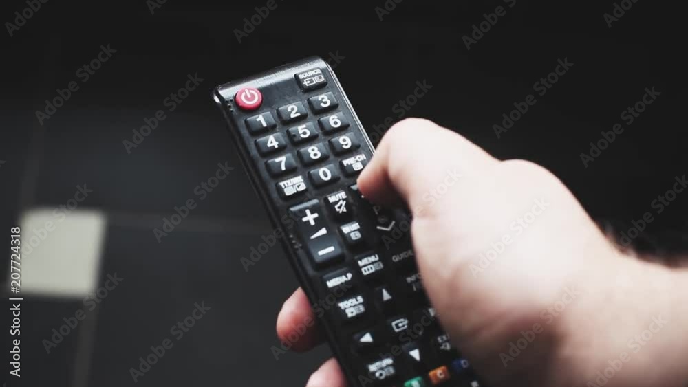 Close up of TV remote changing channels. Channel surfing, focused on the hand and remote control. Close up of TV remote changing channels. Channel surfing, focused on the hand and remote control.