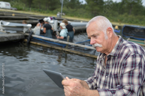 fish farmer checking his tablet at worker