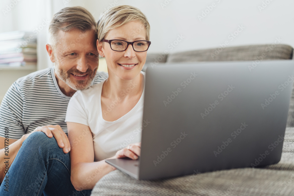 Affectionate middle-aged couple using at a laptop Affectionate middle-aged couple using at a laptop