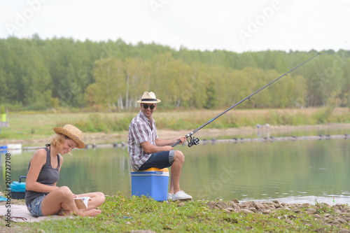 peaceful young couple fishing by the pond in autumn