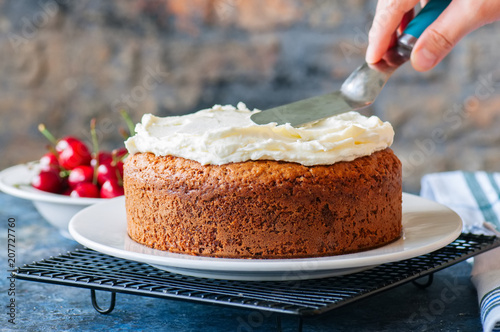 Wall Mural Woman decorating homemade sour cream cake with cream cheese frosting