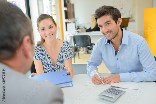 positive smiling agent explaining details of contract young couple