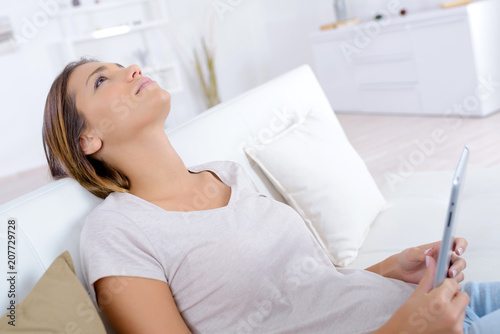 happy young woman sitting on sofa with tablet at home