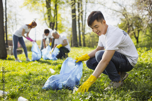 Save nature. Happy male volunteer using garbage bag while gathering litter