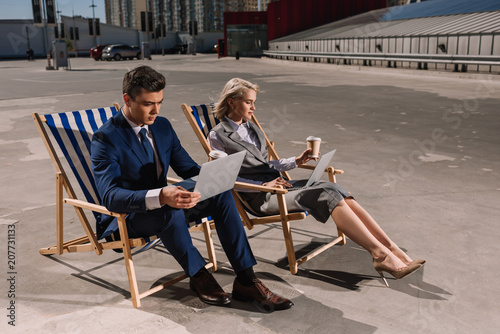 Wallpaper Mural young business people working with laptop while sitting on sun loungers on parking Torontodigital.ca