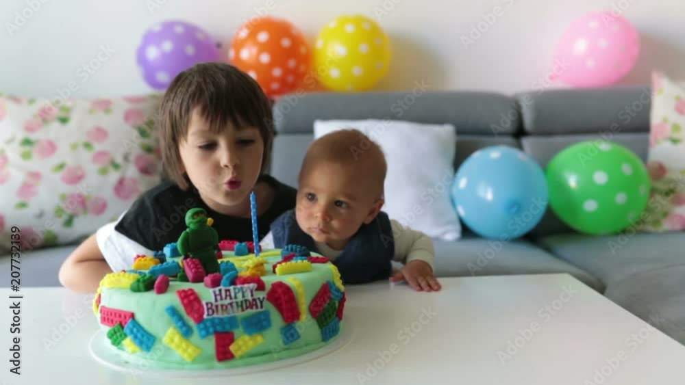 Cute children, boy brothers, celebrating birthday with colorful cake, candles, balloons at home Cute children, boy brothers, celebrating birthday with colorful cake, candles, balloons at home