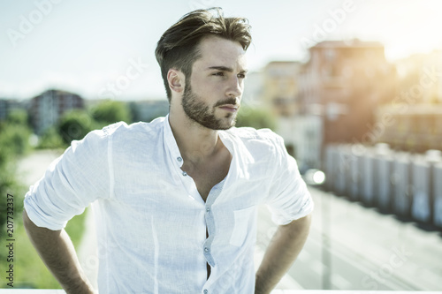 One handsome young man in urban setting in European city, standing