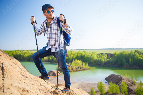 Image of tourist man with backpack with sticks for walking on hill photo