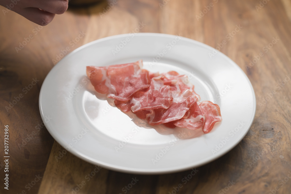 dried coppa ham on white plate