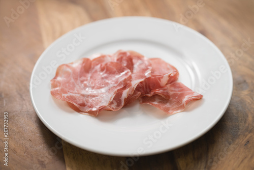 dried coppa ham on white plate