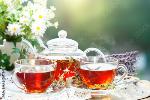 Cup with hot tea with mint and a thyme on a wooden table in a summer garden. Selective focus,