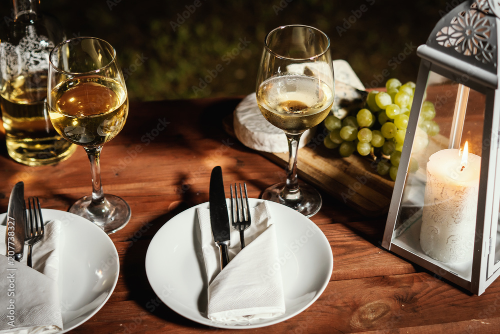 romantic dinner with a glass of wine and snacks on an old wooden table on a summer evening