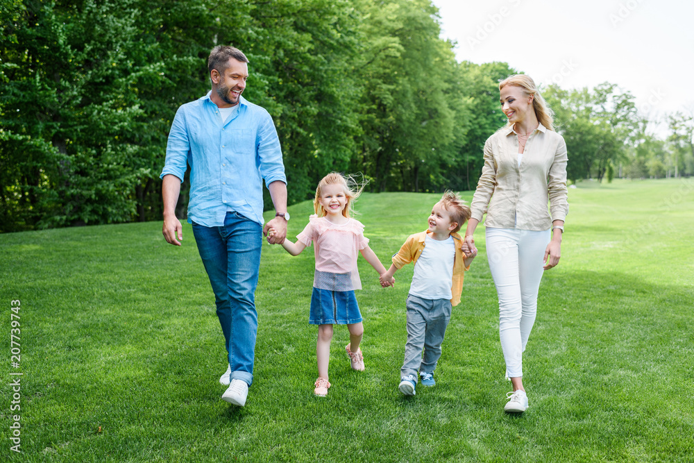 happy family holding hands and walking together in park happy family holding hands and walking together in park