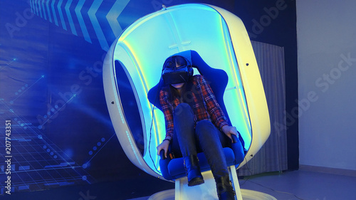 Young girl sitting in virtual reality attraction and feeling scary