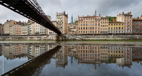 Old footbridge over the Saone river, reflected in a puddle. Lyon, France.