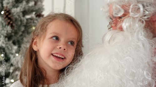 Cute little girl singing Christmas song together with Santa Claus