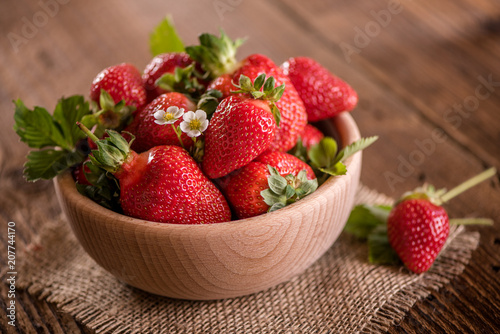 strawberries in wooden bowl on wood table