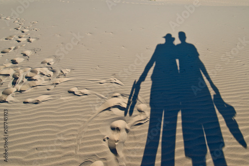 Shadows of pair of tourists on sand dunes