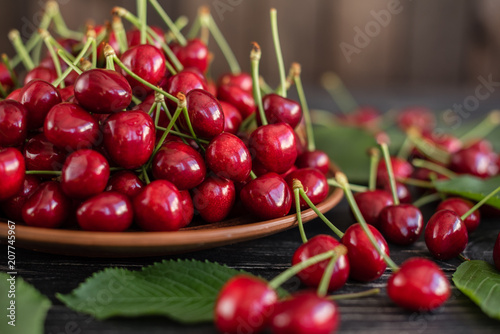 Tasty juicy sweet cherry on a wooden background. It can be used as a background © chernikovatv