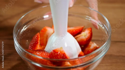 Grinding strawberry for cooking jam photo