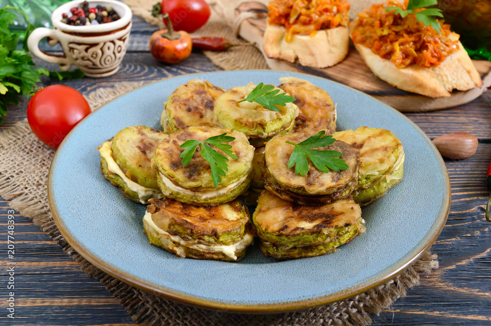 Fried pieces of zucchini with mayonnaise on a ceramic plate on a wooden table. Fried pieces of zucchini with mayonnaise on a ceramic plate on a wooden table.