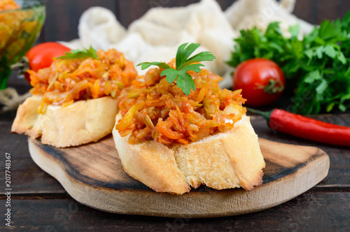 Squash caviar on a crispy baguette on a dark wooden table. Sandwiches with stewed vegetables. Vegan appetizer.