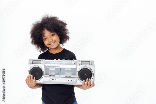 Cute and smiling African American kid holding a musical jukebox isolated over white background