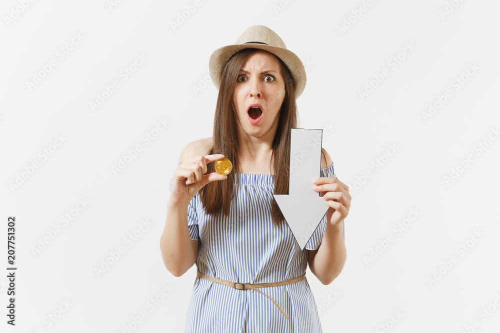 Young shocked sad woman holding bitcoin, coin of golden color, down value fall arrow isolated on white background. Finance and business, online virtual currency concept. Advertising area. Copy space. Young shocked sad woman holding bitcoin, coin of golden color, down value fall arrow isolated on white background. Finance and business, online virtual currency concept. Advertising area. Copy space.